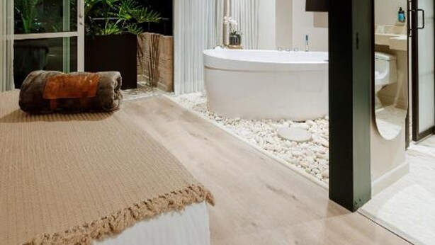 A modern bedroom with a large bed, a bathtub, and a sliding glass door leading to a balcony with plants. - w Loft Estandar Plus (Medellín)