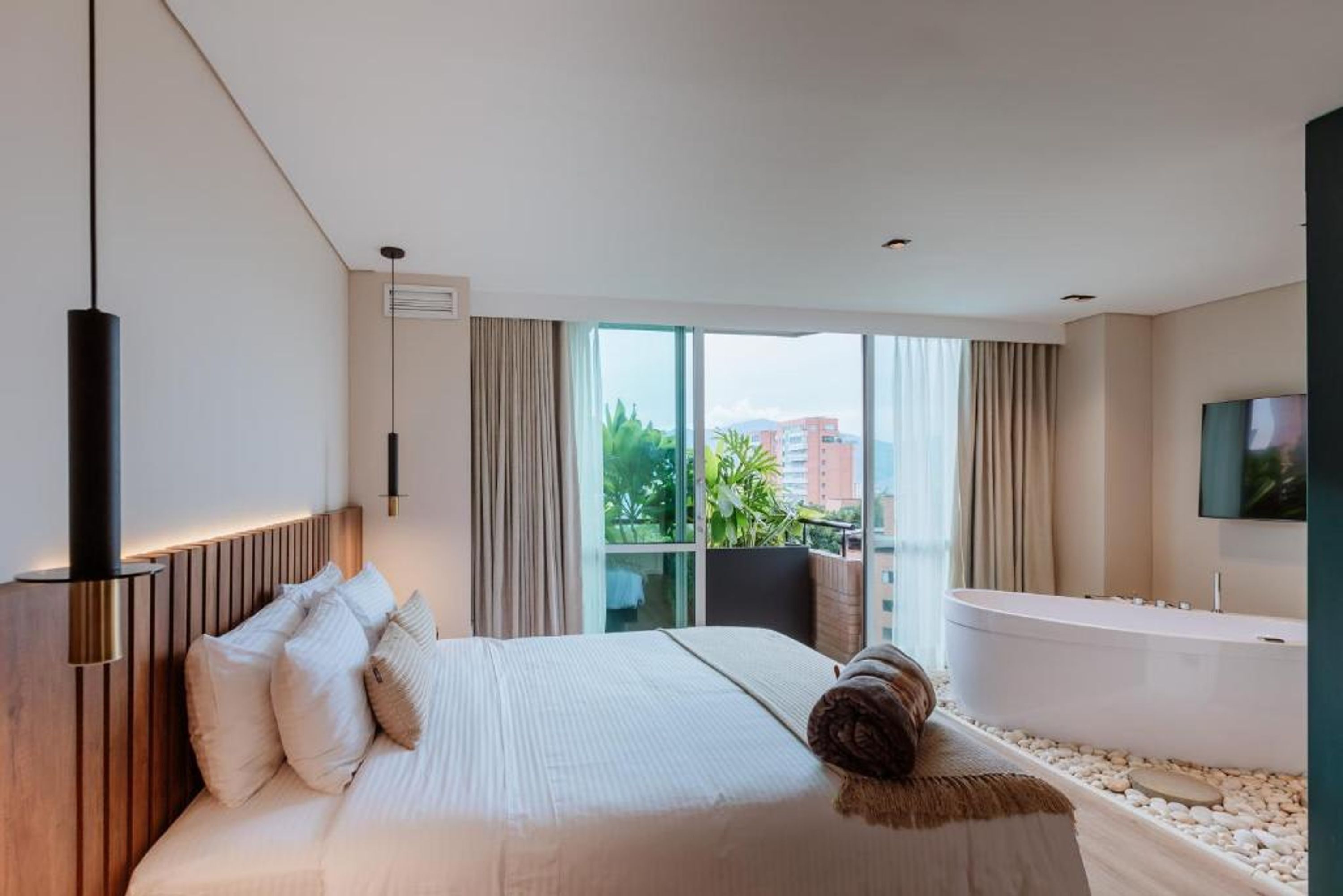 A modern hotel room with a large bed, a bathtub, and a view of the city.