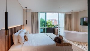 A modern hotel room with a large bed, a bathtub, and a view of the city. - w Loft Estandar Plus (Medellín)