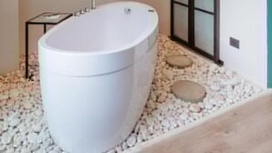 A modern bathroom with a freestanding bathtub, a mounted TV, and a sliding glass door. - w Loft Estandar Plus (Medellín)