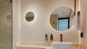 Une salle de bain moderne avec un miroir rond, un lavabo blanc et des toilettes.