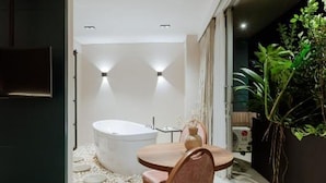 A modern bathroom with a freestanding bathtub, a round wooden table with two chairs, and a potted plant. - w Loft Superior Mountain (Medellín)