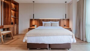 Un dormitorio moderno con una cama grande, cabecera de madera, mesitas de noche y una unidad de almacenamiento empotrada de madera.
