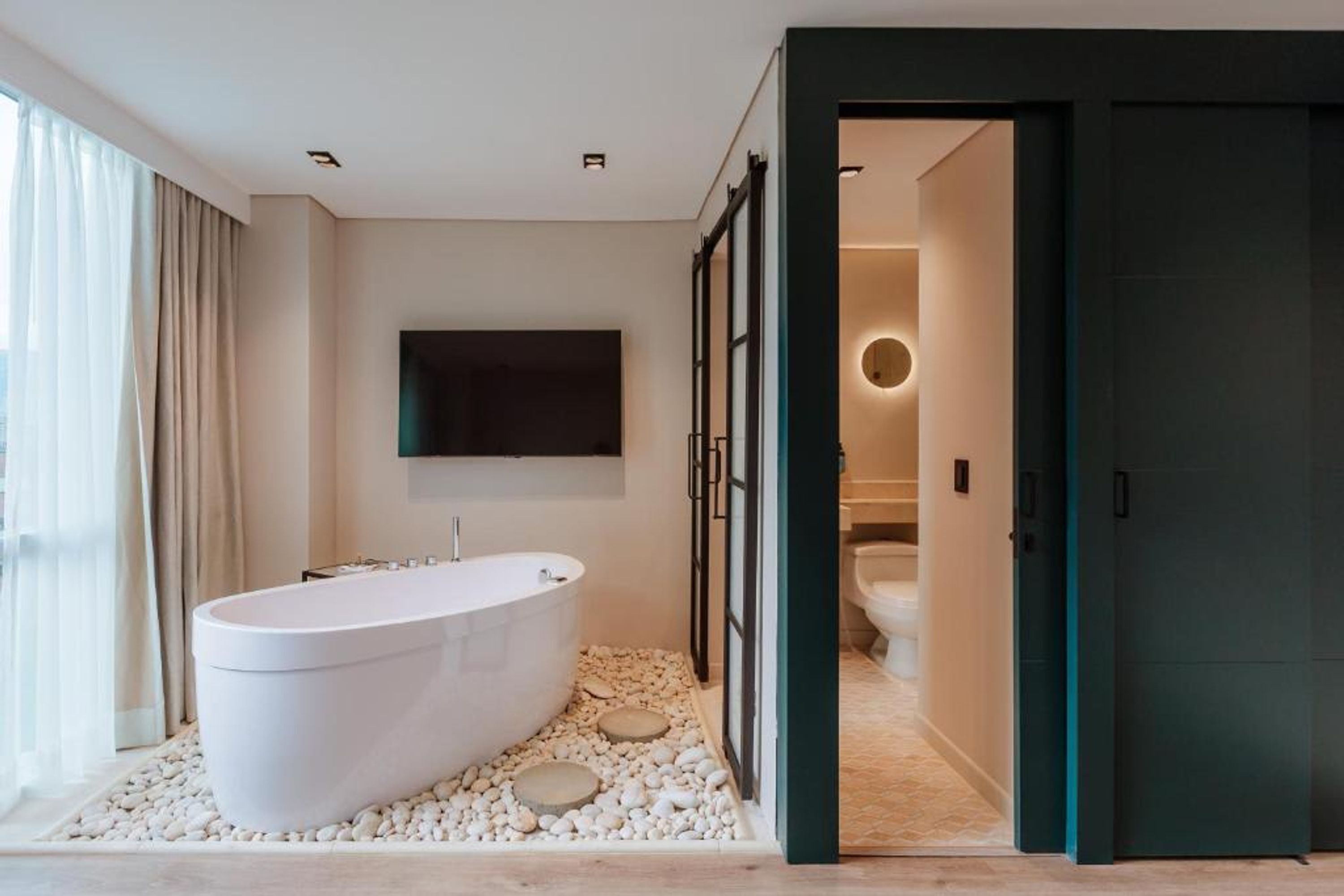 A modern bathroom with a freestanding bathtub, a toilet, and a shower area.