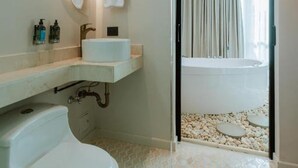 Un baño moderno con un lavamanos blanco, un inodoro y una ba ñera visibles a través de una puerta abierta.