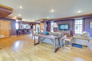 Un salón espacioso con piso de madera, un televisor grande y un sofá.