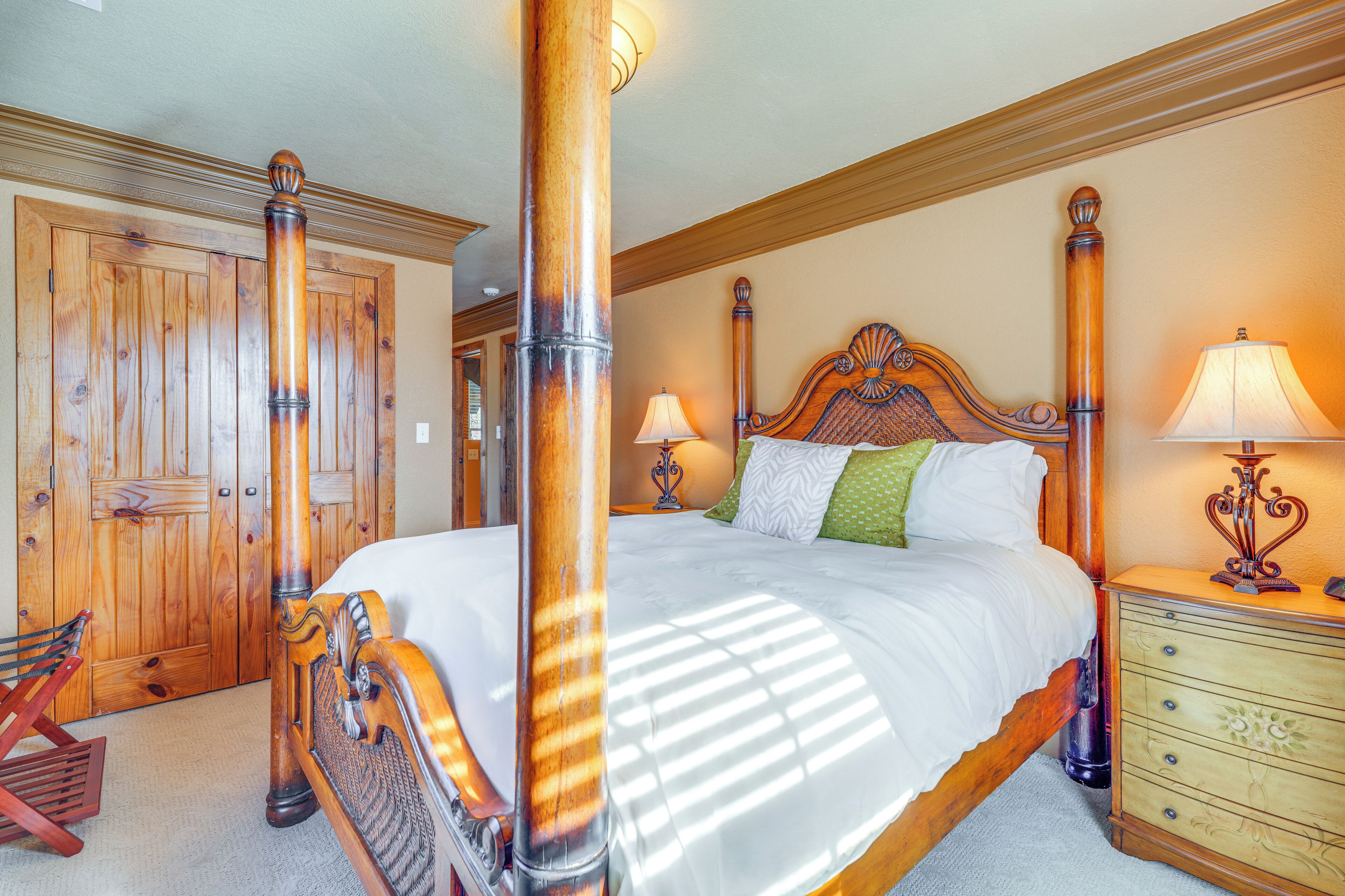 A spacious bedroom with a large bed, wooden headboard, and a nightstand with a lamp.