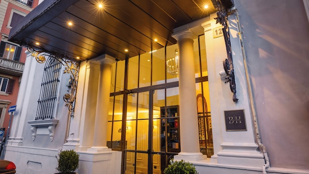A hotel entrance with large glass doors, columns, and a sign indicating room number 12. - Bh Hotel Dimora D'epoca (Rome)