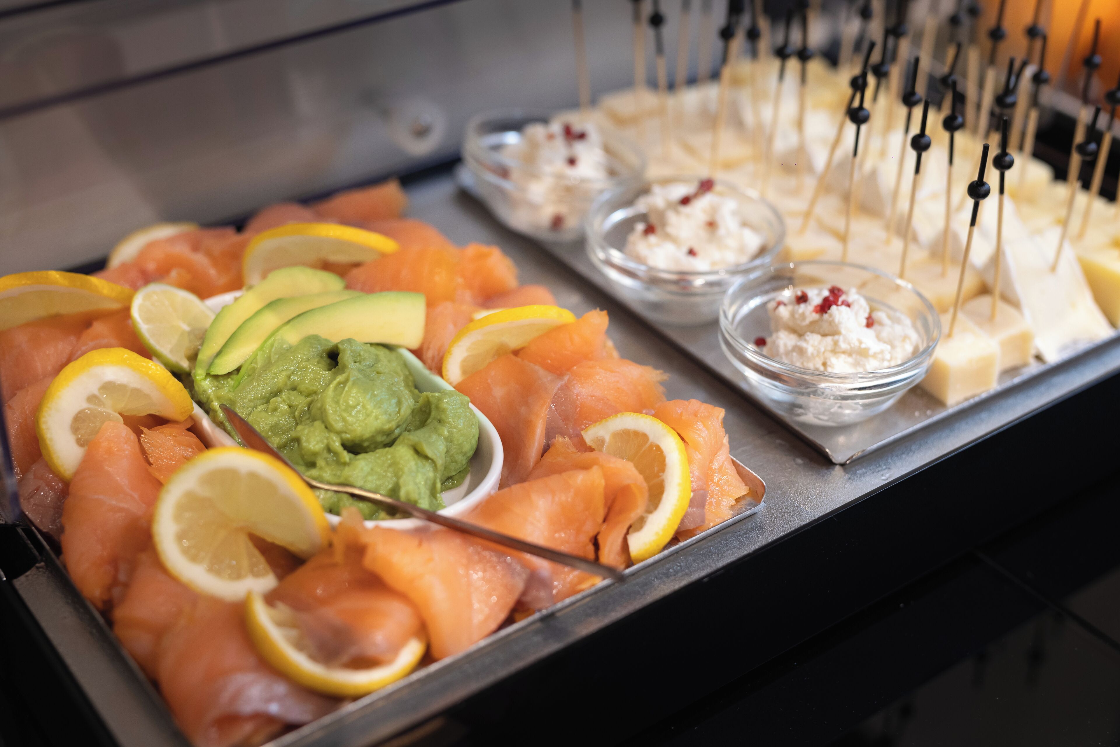 Ein Buffet mit Lachs, Avocado, Zitronenscheiben und verschiedenen Dips.