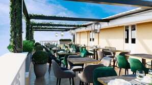 An outdoor dining area with multiple tables and chairs, a pergola with greenery, and a view of the sky. - Bh Hotel Dimora D'epoca (Rome)