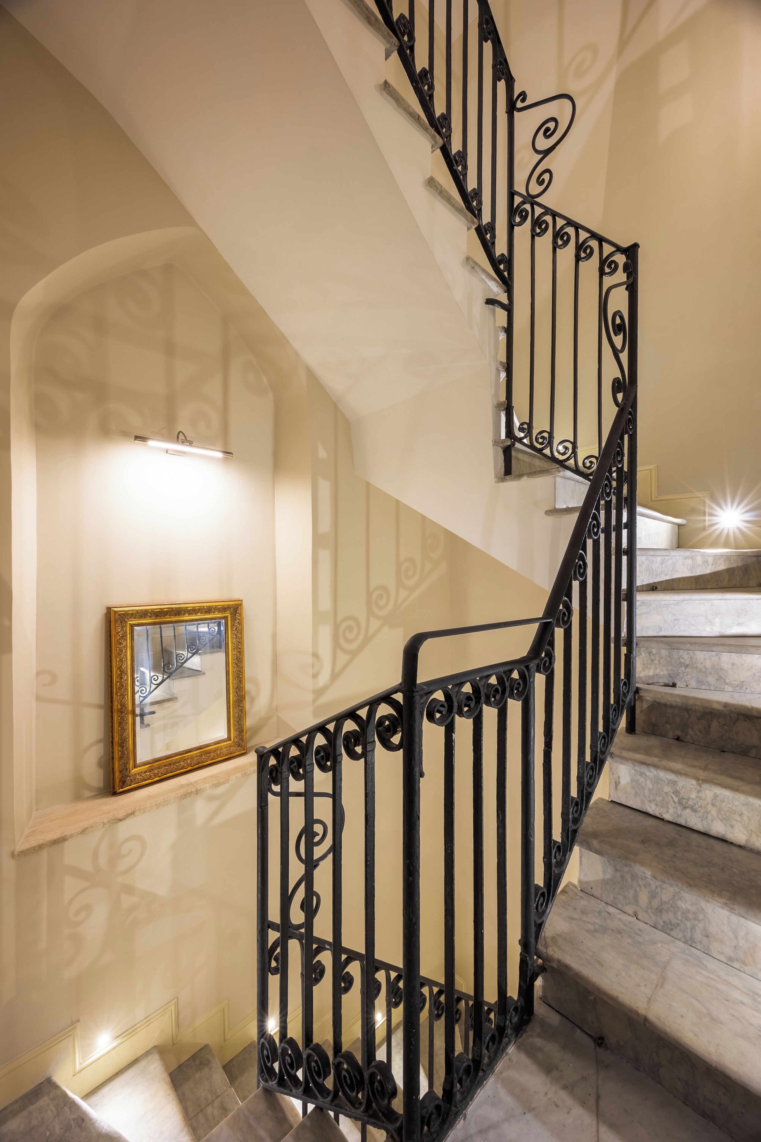 A spiral staircase with ornate black railings and a marble finish.