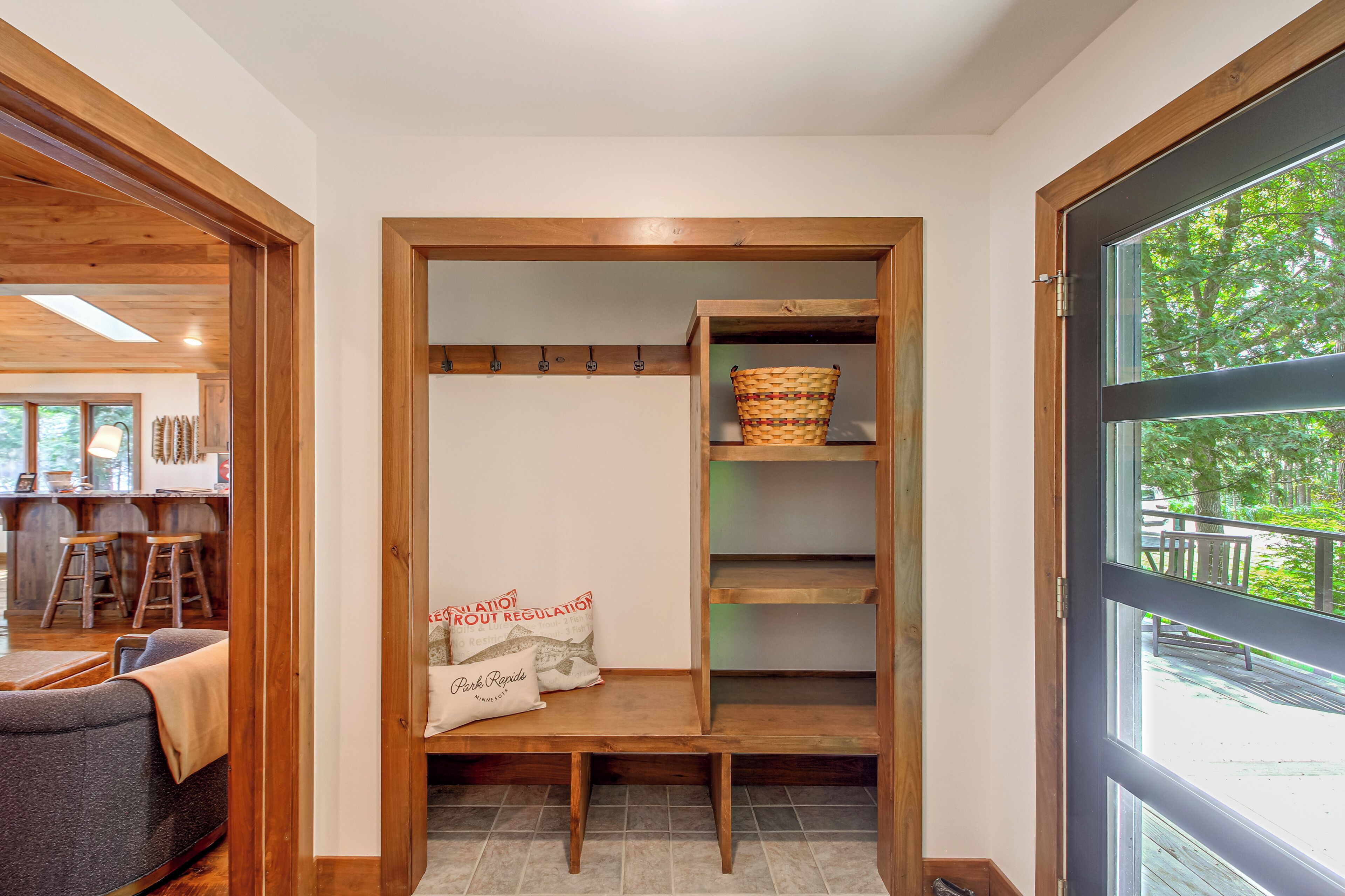 A wooden interior with a bench, a basket, and a pillow with text.