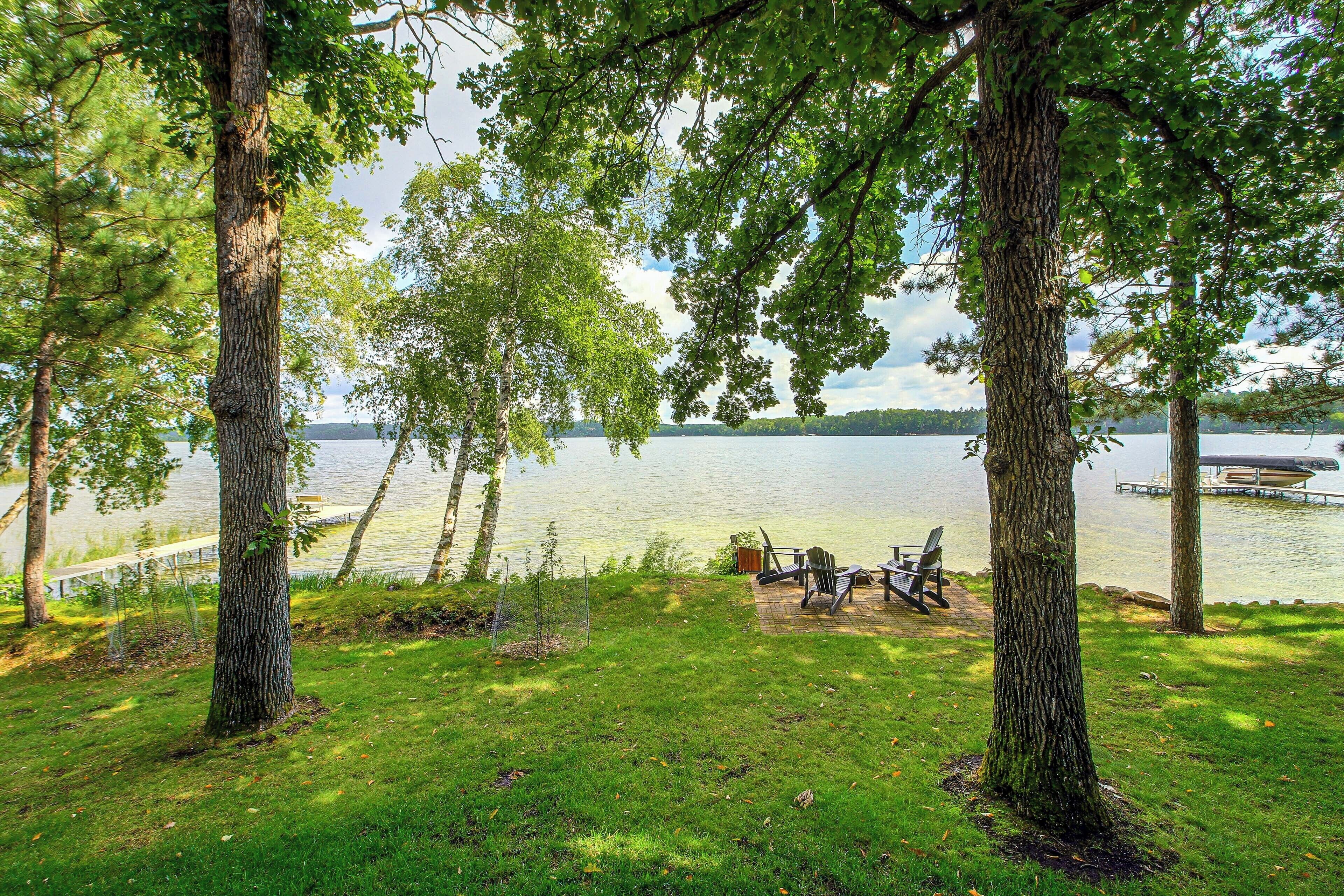 A lakeside view with trees, a dock, and outdoor seating.