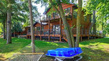 A wooden cabin with a balcony, surrounded by trees.