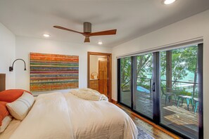 A bedroom with a bed, a ceiling fan, a large window, and a view of the outdoors. - Short Drive to Itasca State Park - Waterfront Home (Park Rapids)