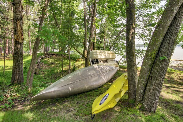 Kayaks leaning against trees in a wooded area.