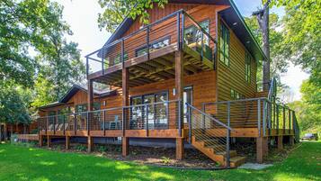 A multi-level wooden cabin with a balcony and outdoor seating area.