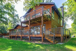 Une cabane en bois à plusieurs niveaux, dotée d’un balcon et d’un espace extérieur aménagé pour s’asseoir.