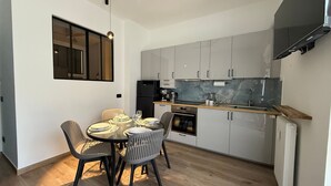 A compact kitchen with a dining area, featuring a round table, chairs, a refrigerator, a stove, and a countertop with a sink. - M P Beach House in Diano Marina (Diano Marina)