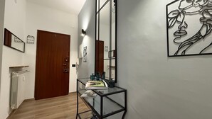 A hallway with a wooden door, a glass table with toiletries, and a wall-mounted mirror. - M P Beach House in Diano Marina (Diano Marina)