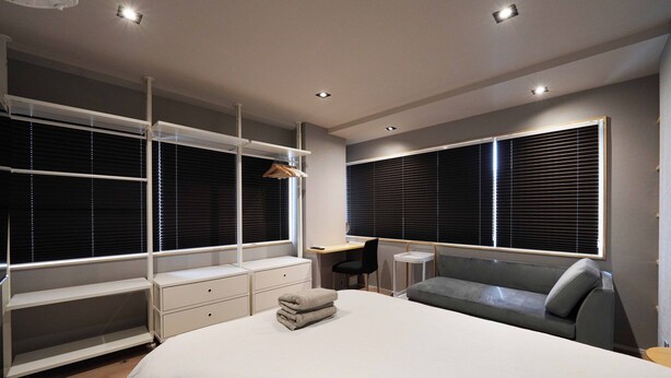A modern bedroom with a large bed, built-in shelving, a desk, and a seating area. - Real Life Iidabashi 1-bedroom Cozy 3pax Hi-end (Tokyo)