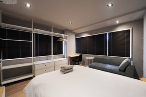 A modern bedroom with a large bed, built-in shelving, a desk, and a seating area. - Real Life Iidabashi 1-bedroom Cozy 3pax Hi-end (Tokyo)