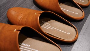 Braune Lederslipper mit sichtbarem Markennamen und Slogan auf der Innensohle.