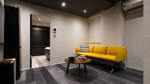 Ein modernes Wohnzimmer mit einem gelben Sofa, einem runden Couchtisch und einem dunklen Boden.