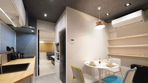 A modern kitchen with a built-in oven, a dining area with a round table and chairs, and a visible air conditioning unit. - Real Life Iidabashi 1-bedroom Luxe 3mins to Subway (Tokyo)