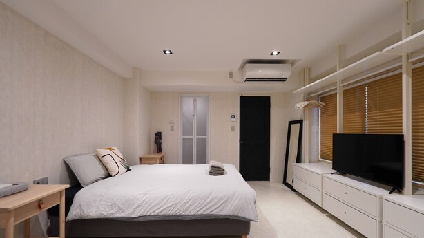 A bedroom with a bed, bedside table, TV, wardrobe, and an air conditioning unit. - Real Life Iidabashi 1-bedroom Luxe 3mins to Subway (Tokyo)
