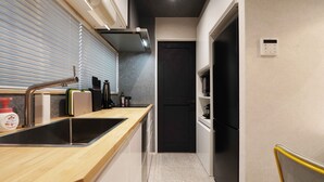 A narrow kitchen with a black door, a wooden countertop, and a built-in sink. - Real Life Iidabashi 1-bedroom Luxe 3mins to Subway (Tokyo)