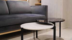 A modern living room with a grey sofa, a round marble table with black legs, and a wooden floor. - Real Life Iidabashi 1-bedroom Luxe 3mins to Subway (Tokyo)