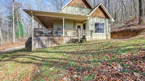 A two-story wooden cabin with a porch and a staircase leading to the entrance.