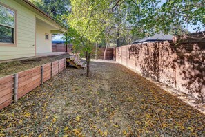 Ein Garten mit Holzzaun, Baum und einem Gebäude mit Fenster.