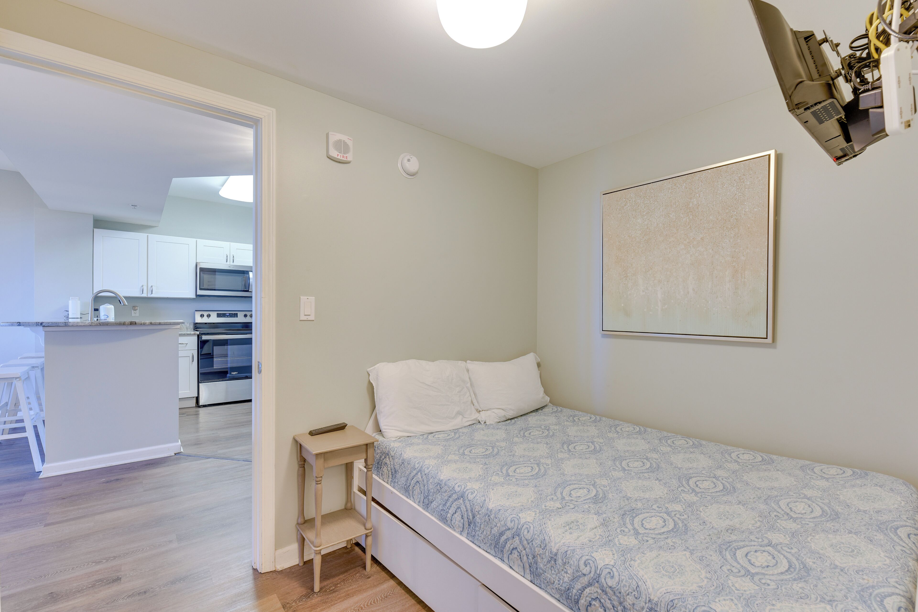 A small bedroom with a bed, a nightstand, and a wall-mounted light fixture.