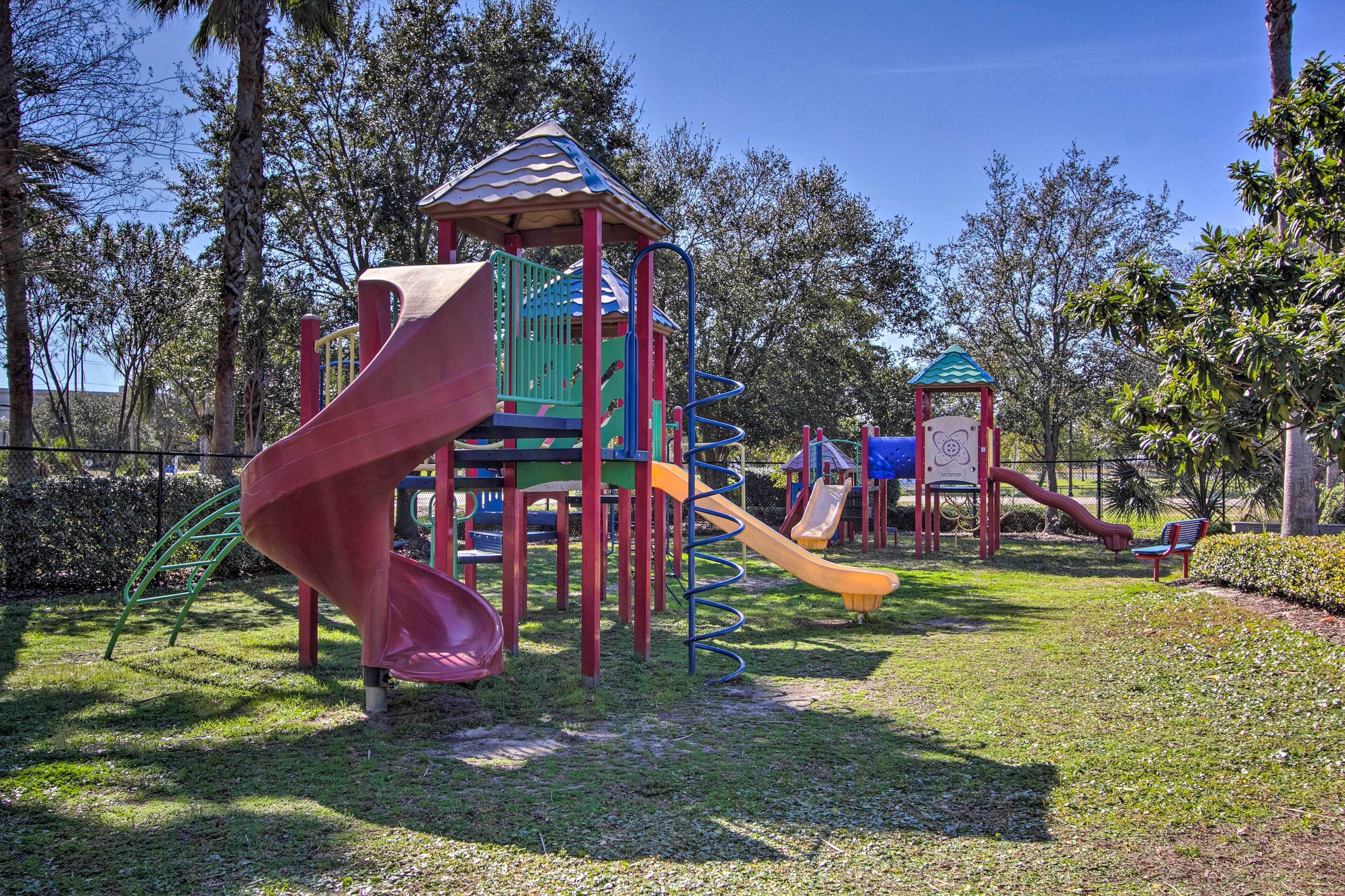 A playground with a red slide, a blue spiral slide, and a green climbing structure.