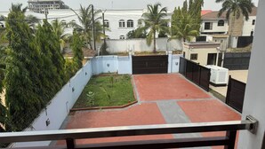Una zona residenziale con un cortile recintato, un edificio sullo sfondo e una palma.