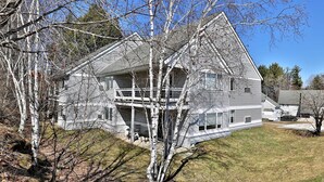 A two-story house with a balcony, surrounded by trees and a clear sky. - Swirl Suite Annex: Studio w/ Kitchenette and Workspace. Discounted Ski Rentals. (Killington)