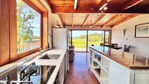 Eine moderne Küche mit einem großen Fenster, Holzbalken an der Decke und Blick ins Freie.