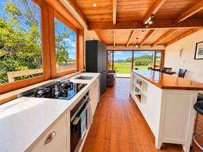 Une cuisine moderne dotée d’une grande fenêtre, d’un plafond en bois et offrant une vue sur l’extérieur.