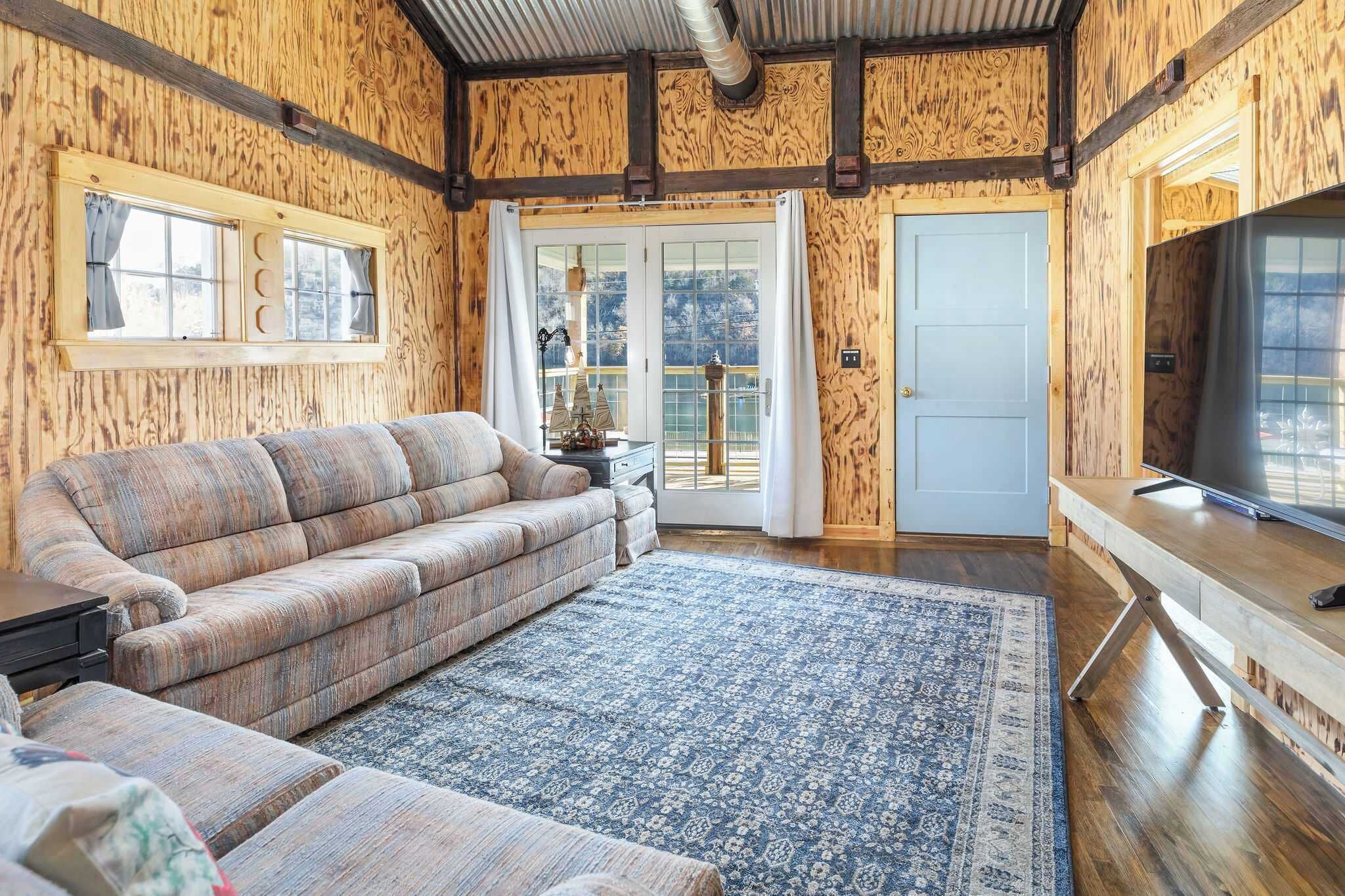 A wooden interior with a sofa, a TV, and a patterned rug.