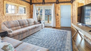 Un interior de madera con un sofá, un televisor y un tapete estampado.