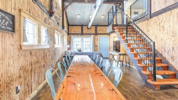 A spacious dining area with a long wooden table, metal chairs, and a staircase with wooden steps.
