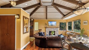 A spacious living room with a large leather sectional sofa, a stone fireplace, and a dining area with a glass table. - 3959 Hedgehog - Walk to Town and Beach, Ocean View (Carmel)