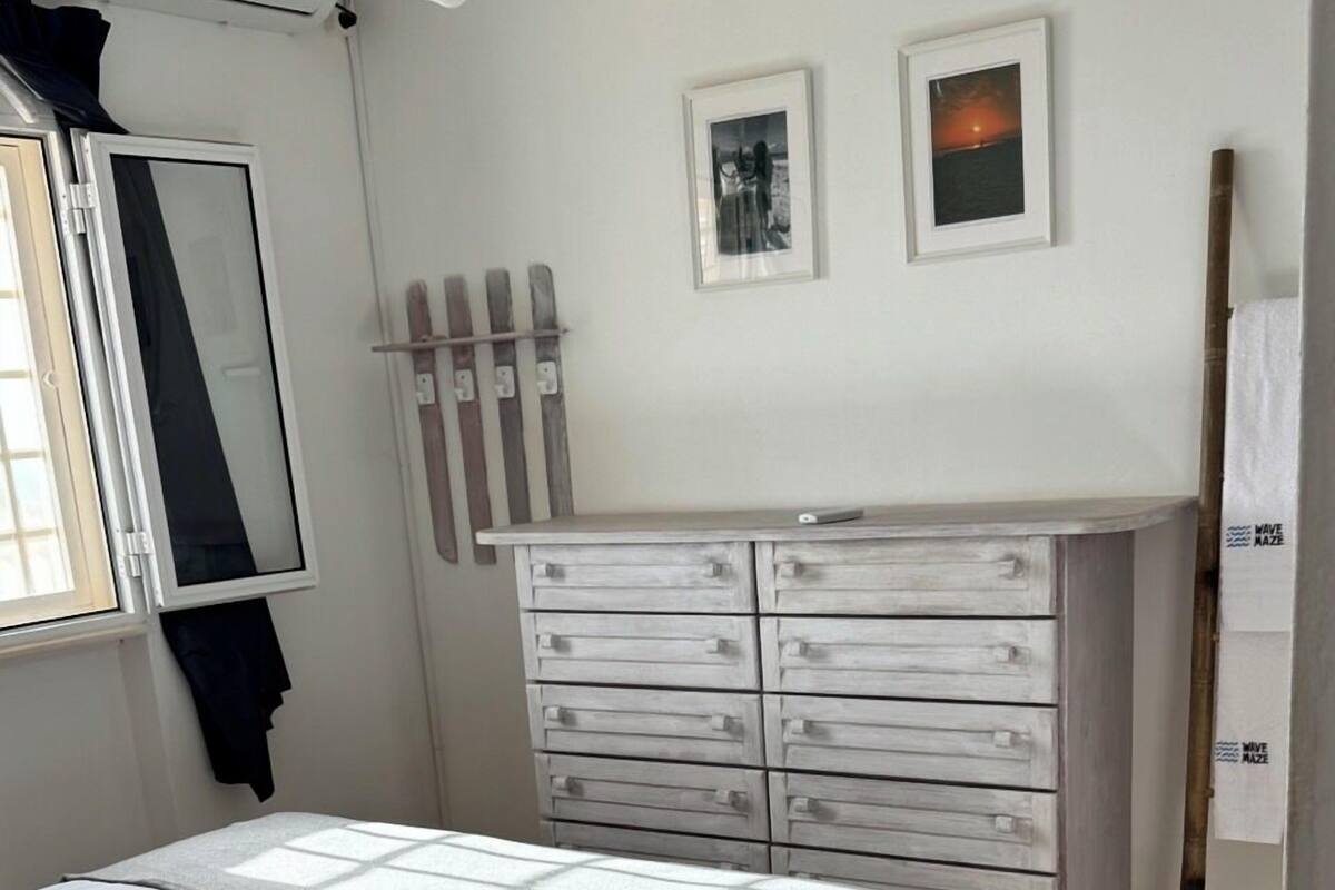A bedroom with a bed, a dresser, and two framed pictures on the wall.