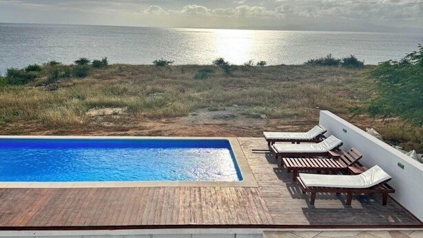 A swimming pool with lounge chairs and a view of the sea. - Wave Maze (Maio)
