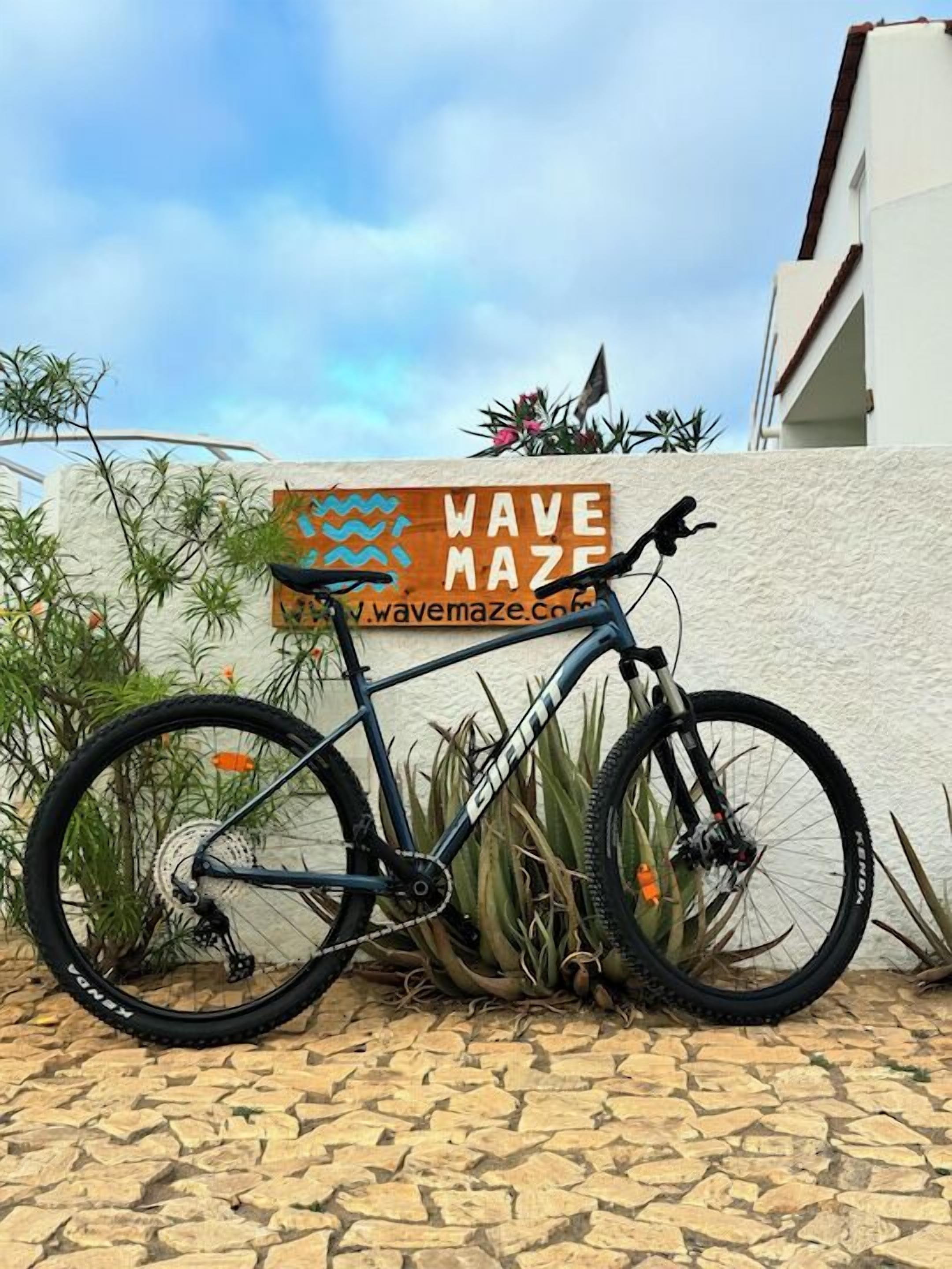 A bicycle parked in front of a sign that reads "WAVE MAZE" with a website address.
