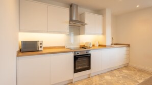 A modern kitchen with white cabinets, a microwave, a toaster, and an oven. - Host Stay Apartment 4 King s Court (Scarborough)