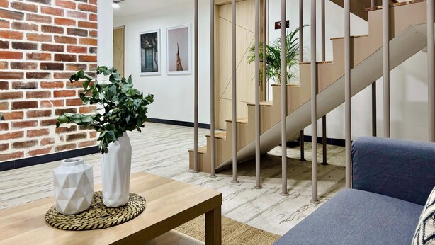 A modern interior with a brick wall, a staircase, and a wooden floor.