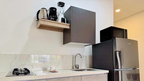 A modern kitchen with a gas stove, a sink, a coffee maker, a blender, and a refrigerator.
